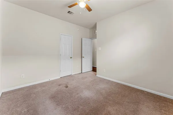 an empty room with a ceiling fan and window