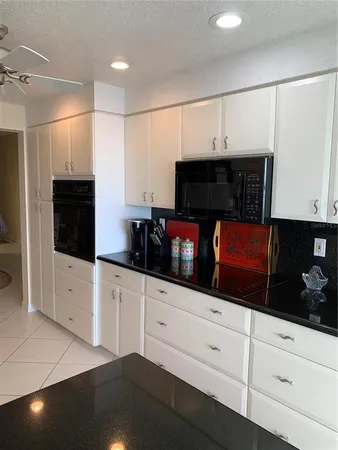 a kitchen with stainless steel appliances kitchen island granite countertop white cabinets and black stove top oven with wooden floor