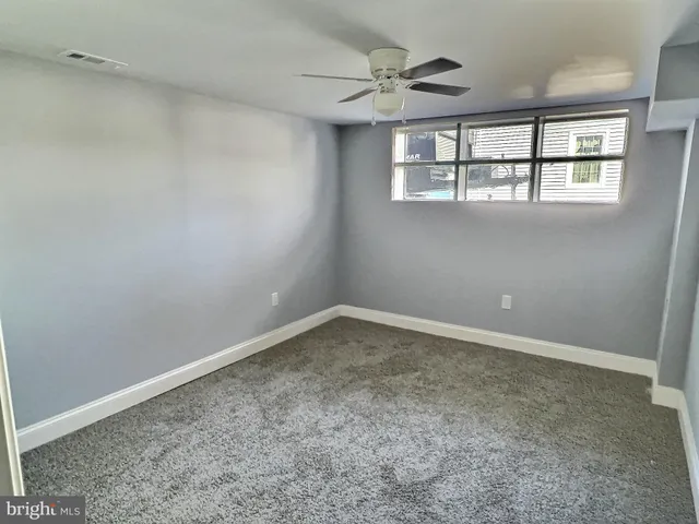 an empty room with windows and ceiling fan
