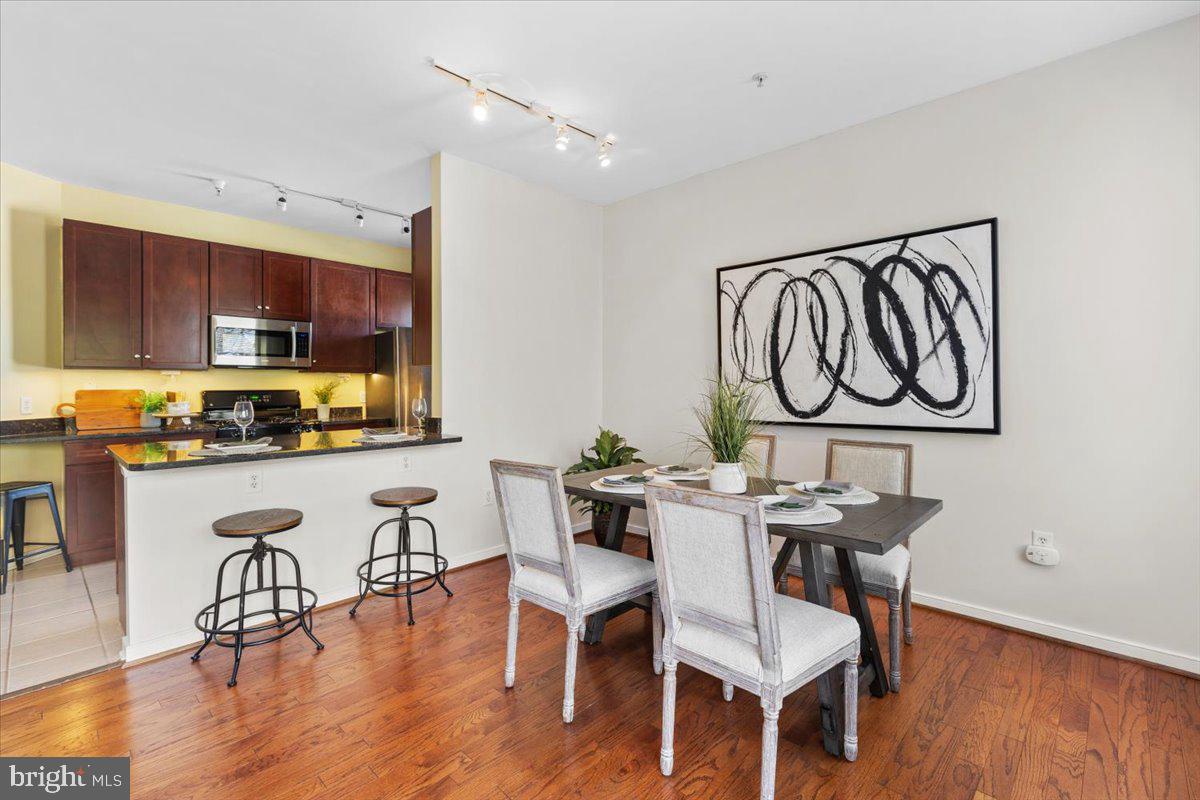 8045 Newell Street, Unit 107 Silver Spring, MD 20910 - Photo 17 of 75 a kitchen with stainless steel appliances granite countertop a table chairs stove and a wooden floor