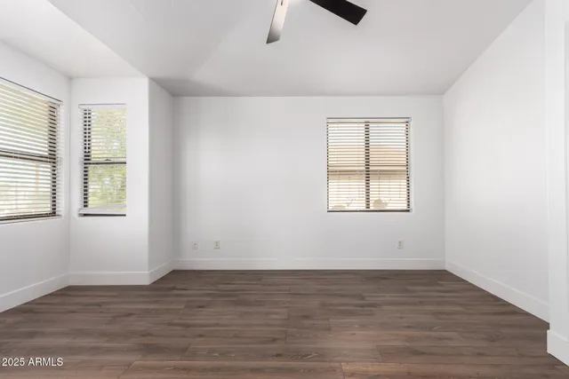 an empty room with wooden floor cabinet and windows