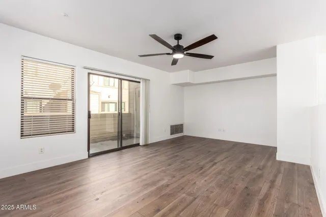 a view of an empty room with a window and wooden floor
