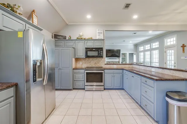 a large kitchen with a large counter top stainless steel appliances and cabinets