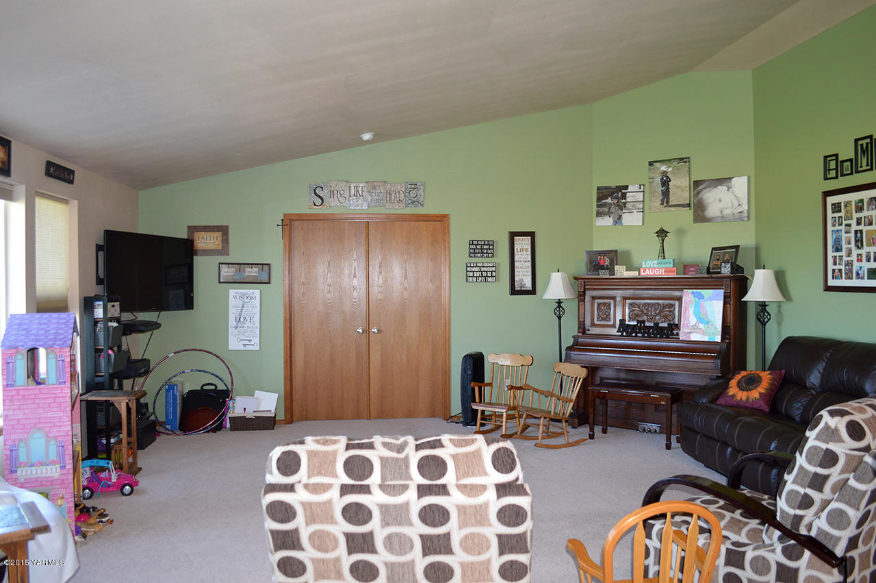 328 Cornue Road Zillah, WA 98953 - Photo 7 of 21 a bedroom with furniture a flat screen tv and a fireplace