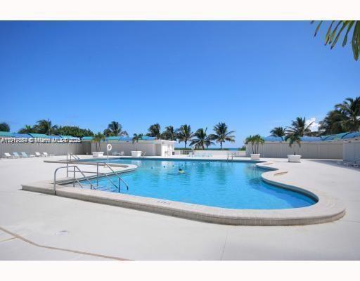 5255 Collins Avenue, Unit 12F Miami Beach, FL 33140 - Photo 43 of 45 a view of a swimming pool with a table and chairs