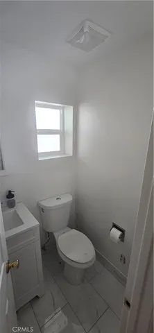 a white toilet sitting next to a white sink and vanity