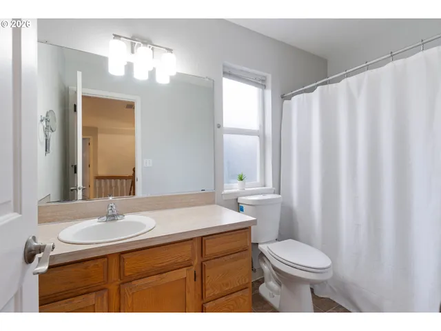 a bathroom with a sink a toilet a mirror a vanity and window