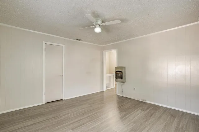 an empty room with wooden floor and ceiling fan