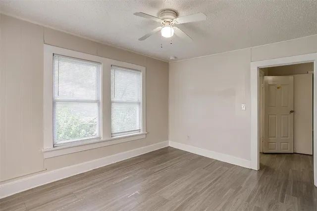 a view of empty room with wooden floor and fan