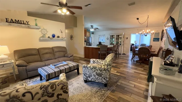 a living room with furniture a flat screen tv and a chandelier