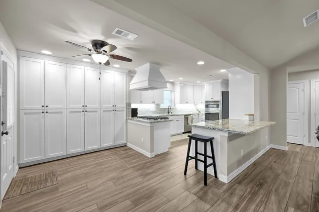 a large kitchen with kitchen island a white cabinets and stainless steel appliances