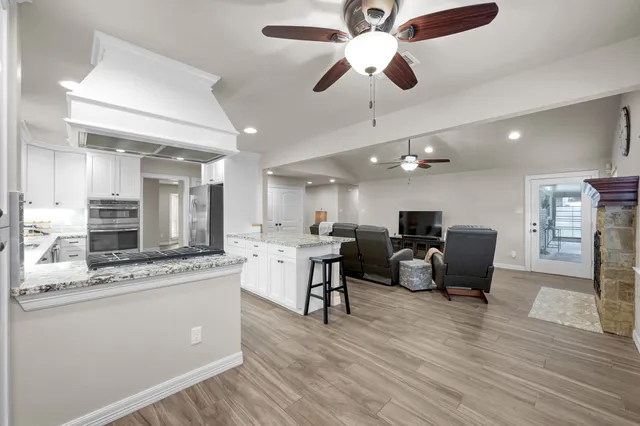 a living room with stainless steel appliances kitchen island granite countertop furniture a fireplace a flat screen tv and a kitchen view