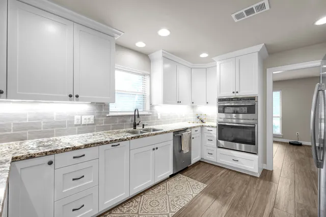 a kitchen with granite countertop white cabinets and white appliances