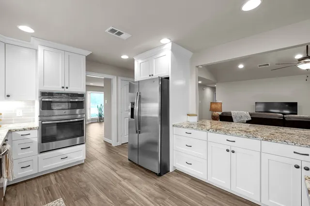 a kitchen with stainless steel appliances kitchen island granite countertop a refrigerator and a stove top oven