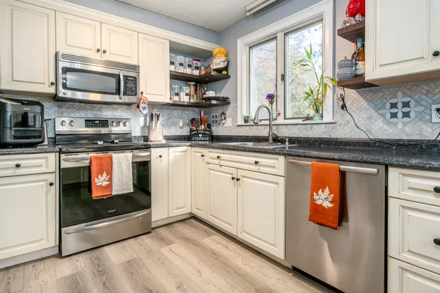 a kitchen with stainless steel appliances granite countertop a stove a sink and a microwave