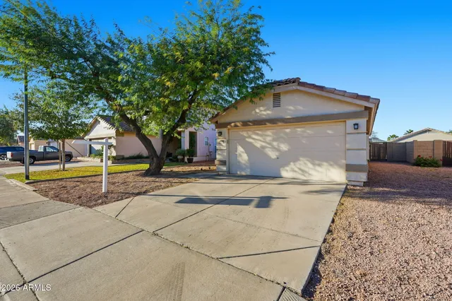 a view of a house with a small yard and large tree