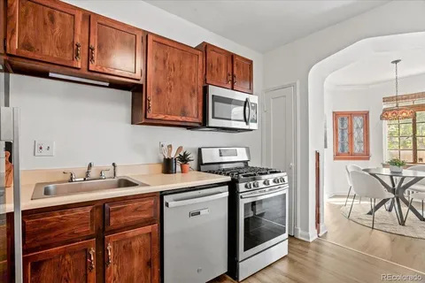 a kitchen with stainless steel appliances granite countertop a stove a sink dishwasher and cabinets with wooden floor