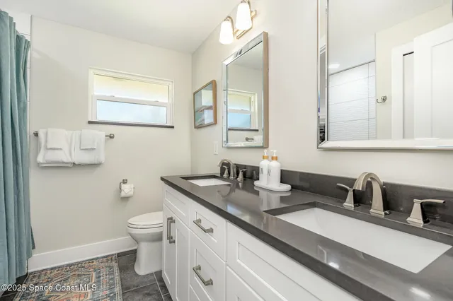 a bathroom with a granite countertop toilet sink and mirror