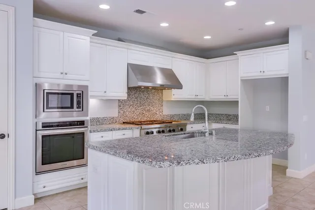 a kitchen with granite countertop white cabinets and stainless steel appliances