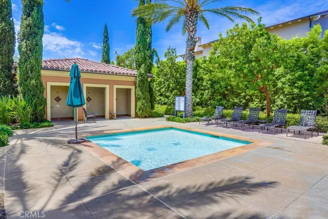 swimming pool view with a tub and trees in the background