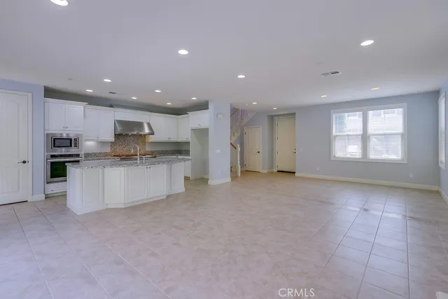 a view of kitchen with refrigerator and white cabinets