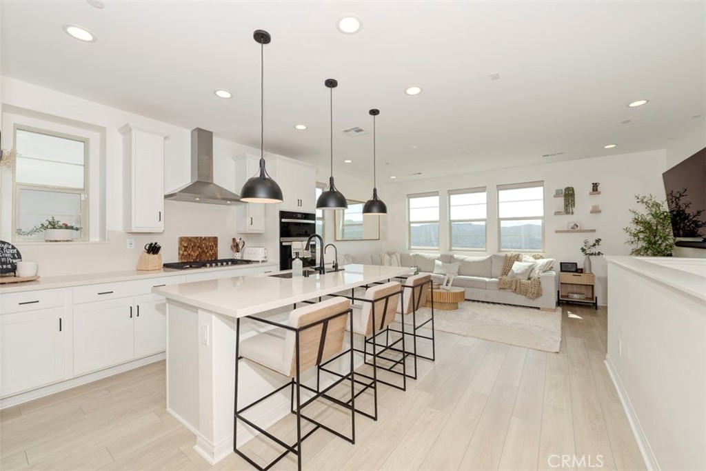 861 Cornelia Way Rancho Mission Viejo, CA 92694 - Photo 3 of 39 a kitchen with stainless steel appliances kitchen island granite countertop a stove a sink and white cabinets with wooden floor