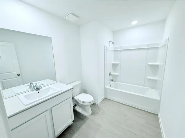 a bathroom with a bathtub shower sink vanity mirror and toilet