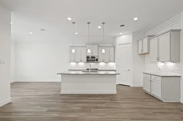 a view of kitchen with granite countertop sink microwave and cabinets