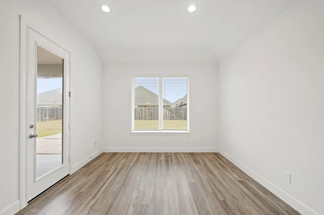an empty room with wooden floor and windows