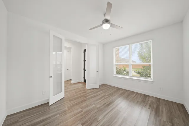 an empty room with wooden floor and windows