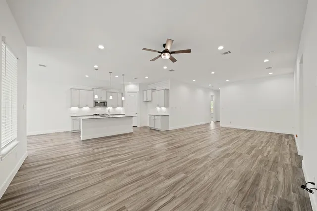 a view of kitchen with kitchen island a sink dishwasher and a stove with wooden floor