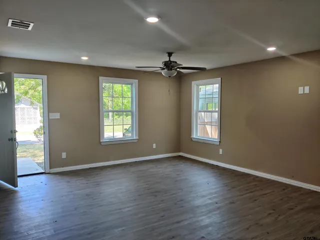 a view of an empty room with wooden floor and a window