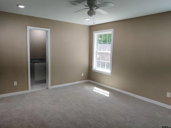 an empty room with chandelier fan and windows