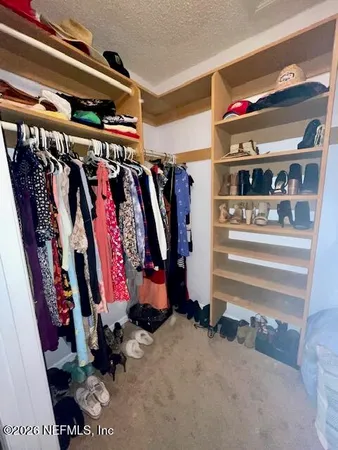 a view of walk in closet with clothes and shoes