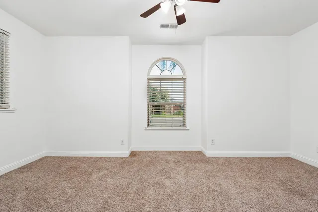 an empty room with windows and fan