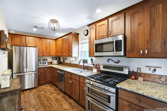 a kitchen with stainless steel appliances granite countertop a sink stove and wooden cabinets