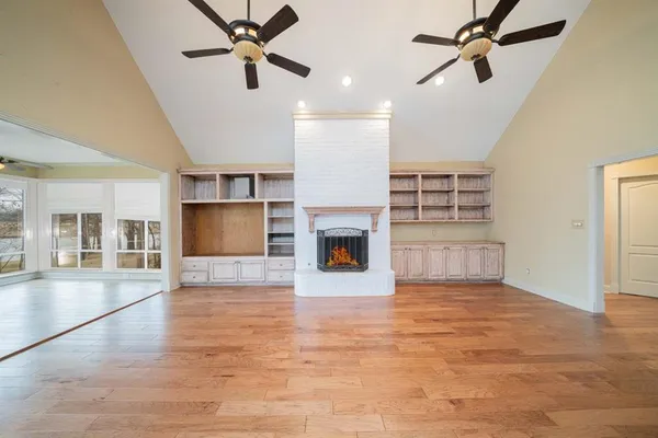 a view of a livingroom with a fireplace a ceiling fan and windows