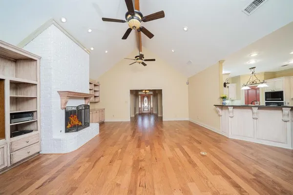 a view of a livingroom with a fireplace a ceiling fan and windows