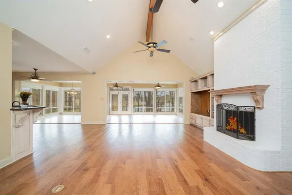 an empty room with wooden floor fireplace and windows