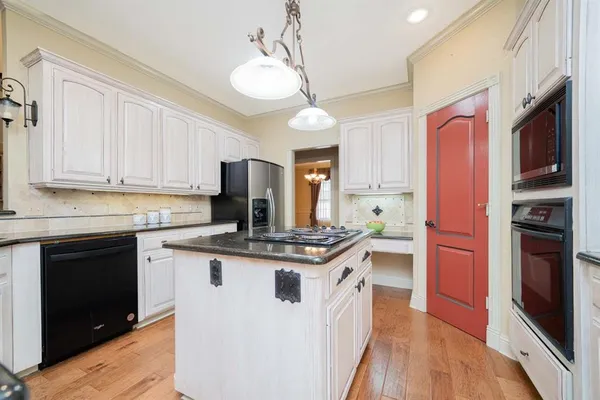 a kitchen with stainless steel appliances granite countertop a stove top oven a refrigerator a sink and dishwasher with white cabinets