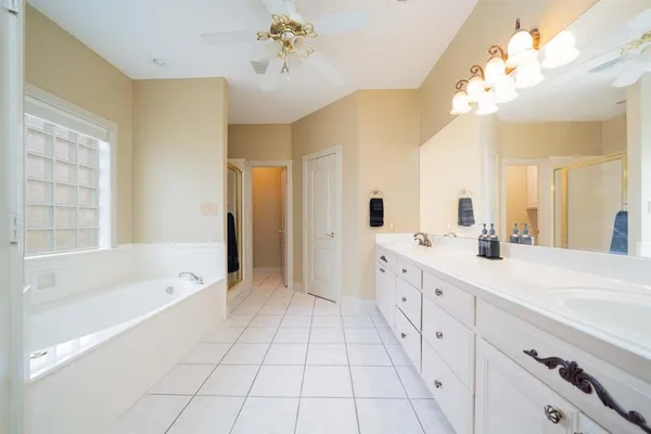 a spacious bathroom with a double vanity sink a mirror a bathtub and a shower