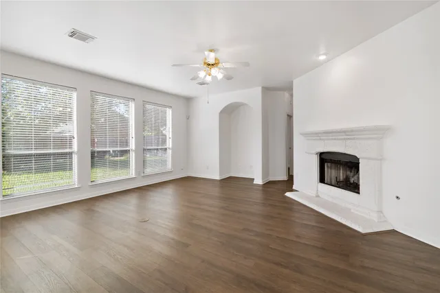 a view of an empty room with a window and wooden floor
