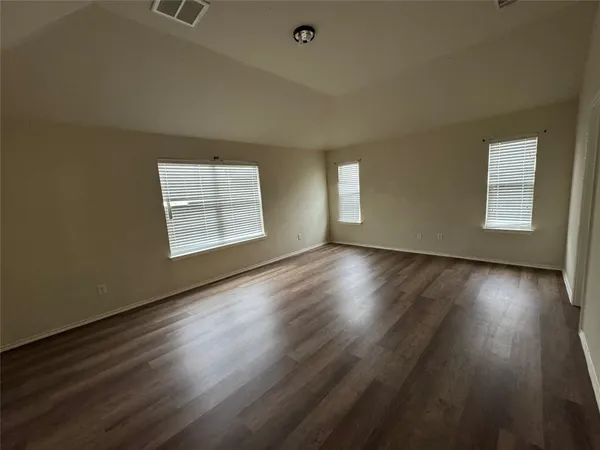 an empty room with wooden floor and windows