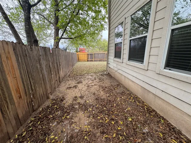a view of a backyard with large trees and wooden fence