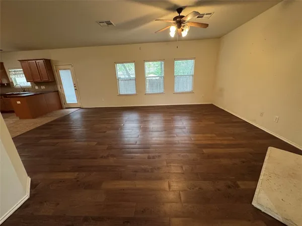 a view of an empty room with window and wooden floor