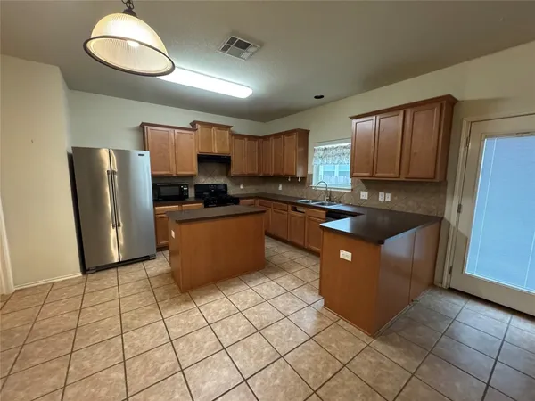 a kitchen with stainless steel appliances granite countertop a refrigerator a sink a stove a microwave and island