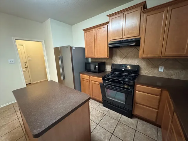 a kitchen with granite countertop a refrigerator stove and sink