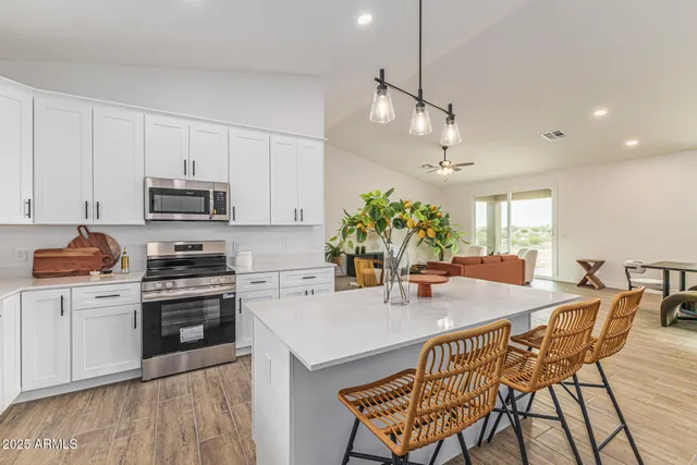 a kitchen with stainless steel appliances granite countertop a stove top oven a sink a dining table and chairs