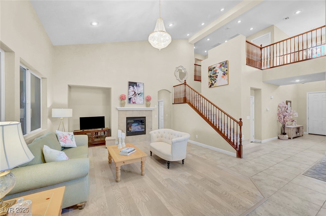 9725 Sandy Turtle Avenue Las Vegas, NV 89149 - Photo 11 of 51 Living room with high vaulted ceiling, stairs, recessed lighting, a tile fireplace, and wood finished floors
