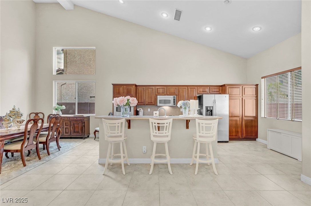 9725 Sandy Turtle Avenue Las Vegas, NV 89149 - Photo 16 of 51 Kitchen with a kitchen bar, appliances with stainless steel finishes, high vaulted ceiling, light countertops, and a center island with sink